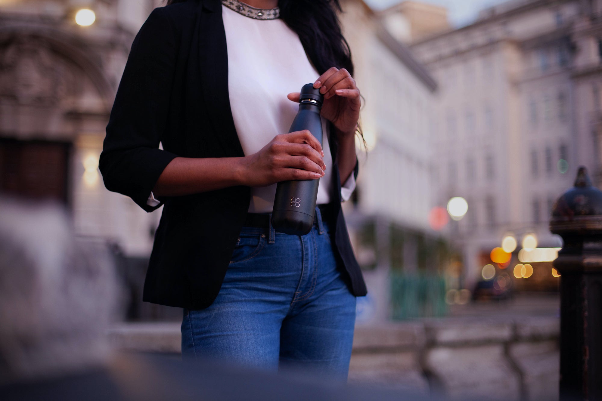 Lady holding a black metal bottle in a city center
