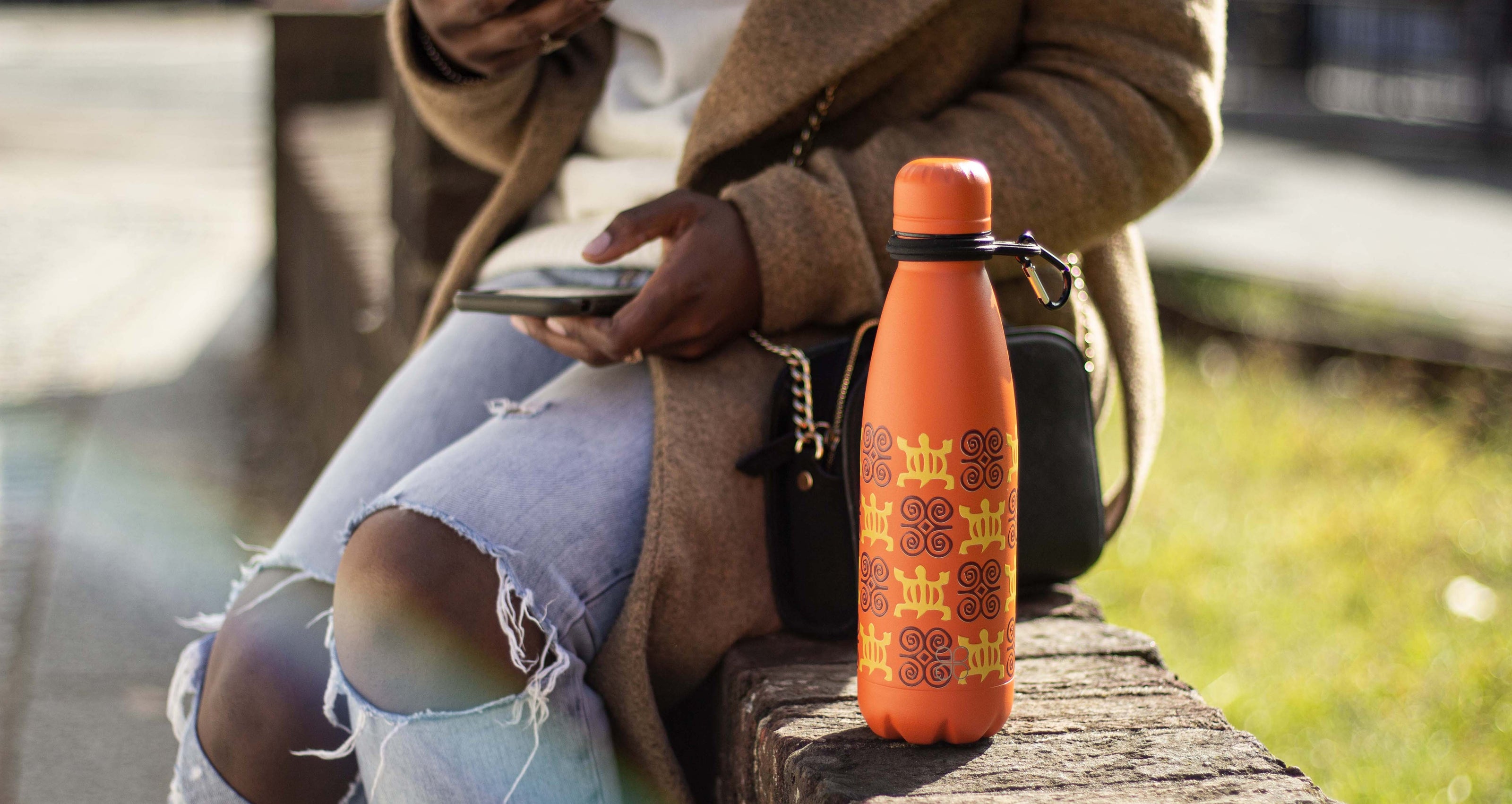 Lady sitting next to the Burnt orange Adinkra Brim's Bottle 