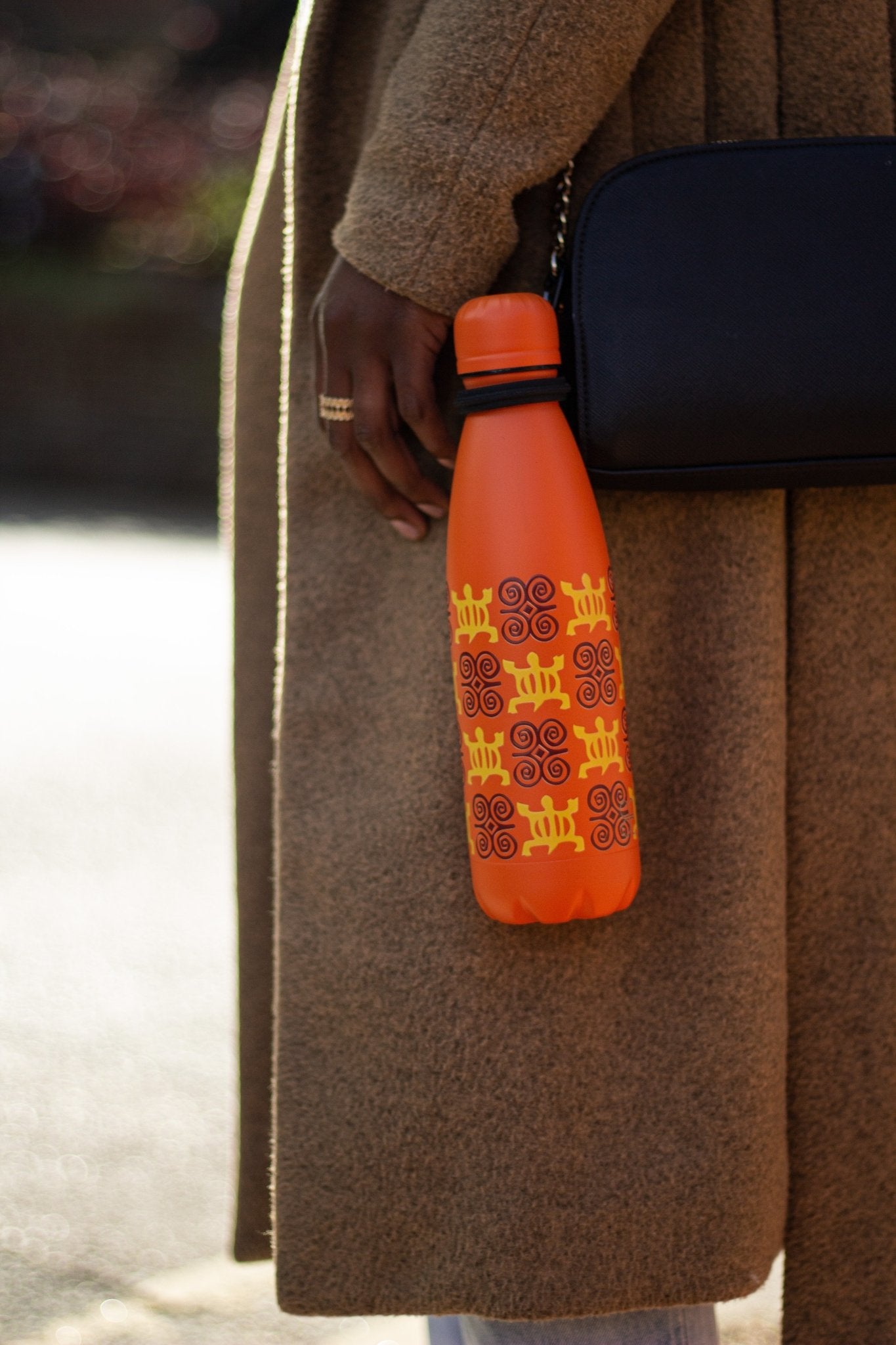 Orange bottle hanging off lady's hand bag