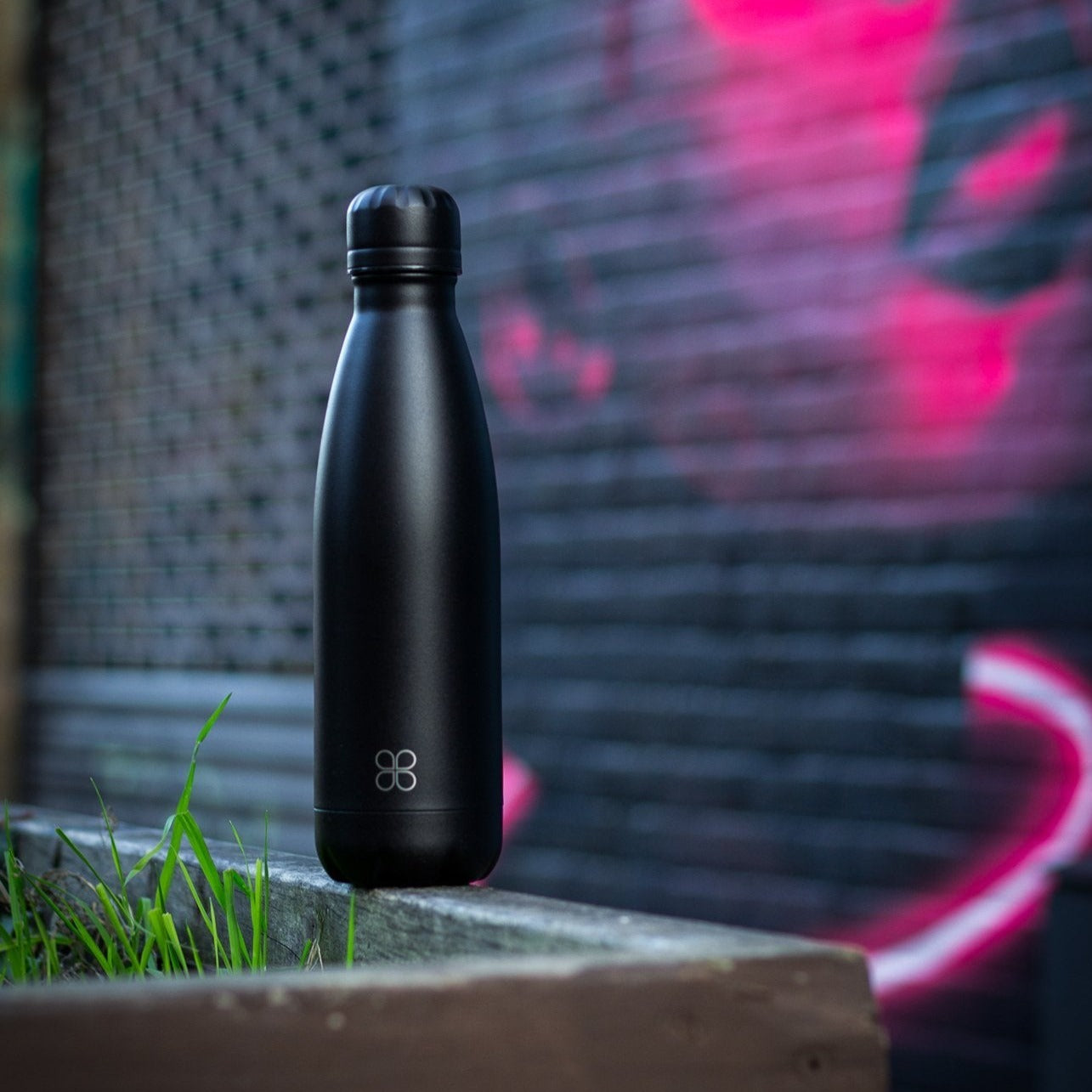 Black water bottle sitting in front of a mural.