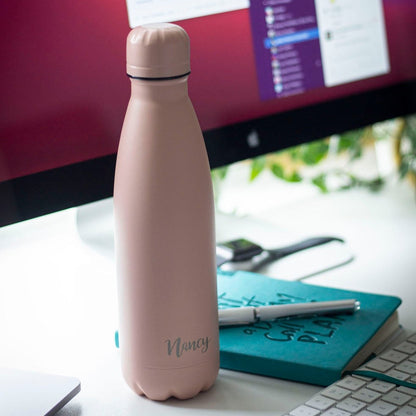 Water bottle engraved with name one a desk.